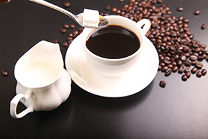 Tasse Kaffe, Kännchen Milch und Zucker.