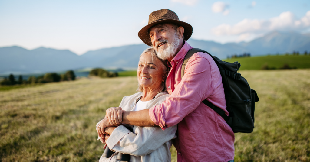 Monika und Klaus genießen gemeinsam eine Wanderung in einer sonnigen Berglandschaft.
