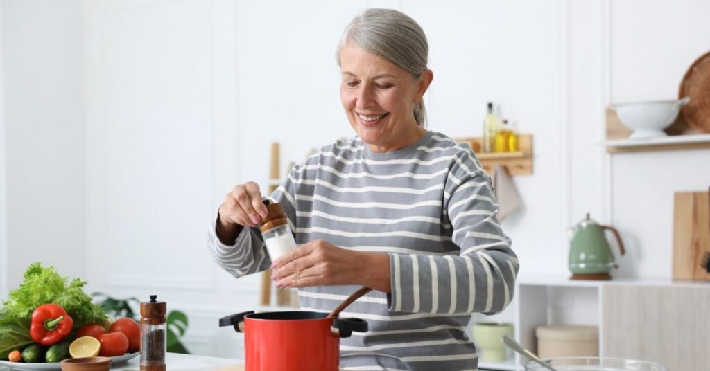 Gichtampel für den Alltag: ältere Frau beim Kochen mit frischem Gemüse als Beispiel für eine gichtfreundliche Ernährung.