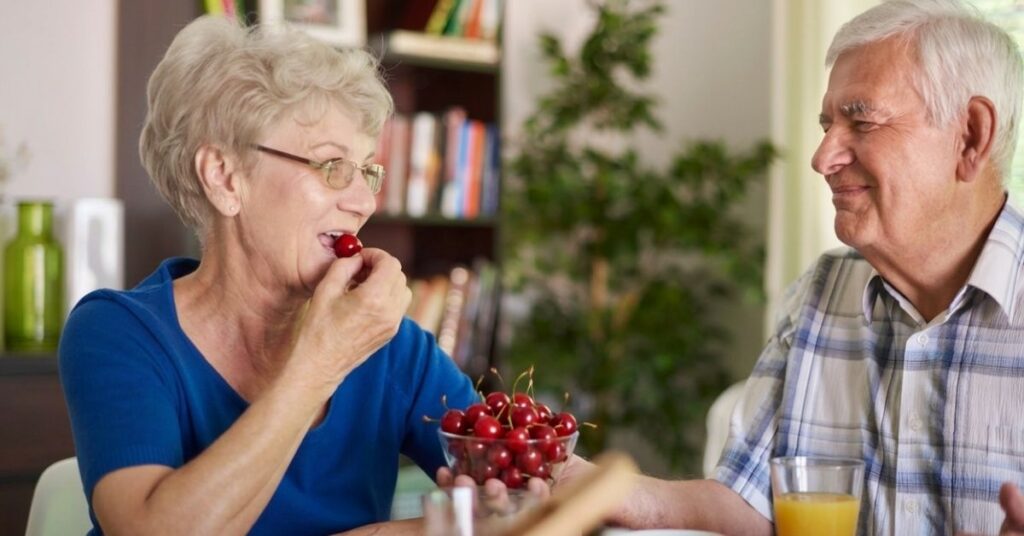 Älteres Paar isst frische Sauerkirschen – Montmorency-Sauerkirschen werden mit einer möglichen Unterstützung bei erhöhten Harnsäurewerten in Verbindung gebracht.