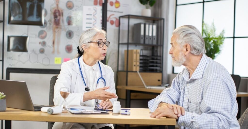 Ärztin spricht mit Patient über Behandlungsmöglichkeiten – eine ärztliche Untersuchung ist wichtig für die richtige Behandlung bei Gicht.