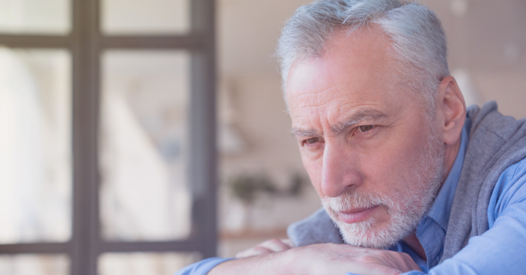 Nachdenklicher älterer Mann sitzt am Tisch – erhöhte Harnsäure bleibt oft lange unbemerkt, bis Beschwerden wie Gicht auftreten.