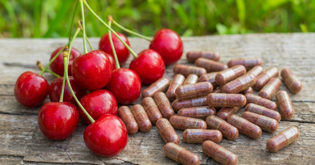 Sauerkirschen neben Kapseln mit Kirsch-Extrakt – Sauerkirschpräparate können eine praktische Möglichkeit sein, natürliche Pflanzenstoffe zur Unterstützung bei erhöhter Harnsäure aufzunehmen.