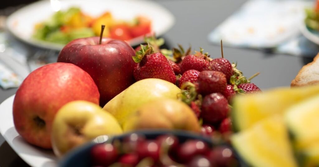 Frisches Obst mit Äpfeln, Erdbeeren und weiteren Früchten als Bestandteil einer purinarmen Ernährung bei Gicht.