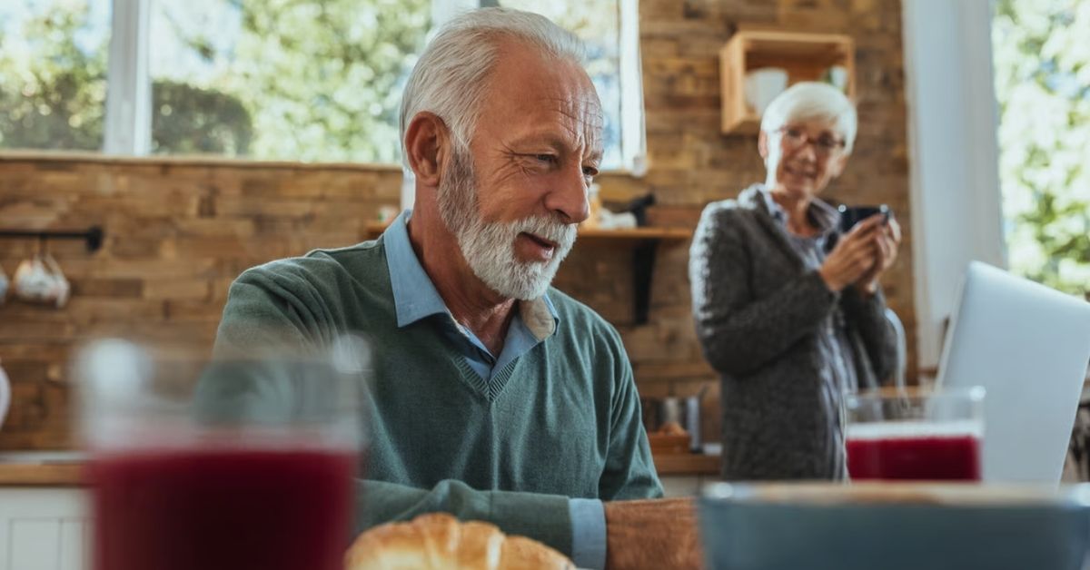 Älteres Paar in der Küche mit zwei Gläsern rotem Saft auf dem Frühstückstisch